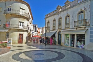 Une place pavée bordée de bâtiments historiques, d’un bar et de boutiques.