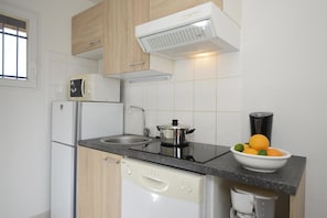 A compact kitchen with a built-in dishwasher, a microwave, a stove, and a sink. - Apartment in Hilltop Setting (Vallon Pont D'arc)