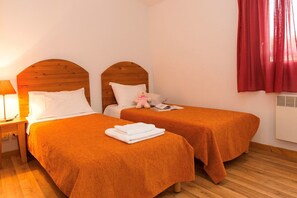 A hotel room with two beds, wooden headboards, a bedside table with a lamp, a red curtain, and a window. - Nature Retreat with Terrace (VALLON PONT D'ARC)