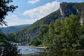 Een rivier met een brug, omgeven door dicht bos en een klif.