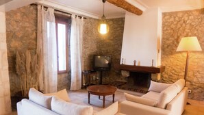 Un soggiorno con parete in pietra, camino, televisore e divano.