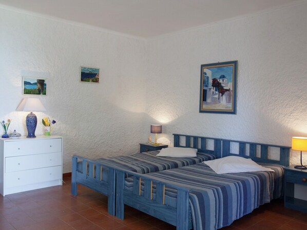 A bedroom with two beds, a dresser, and a nightstand. - Romantic Retreat in Cargèse (Cargese)