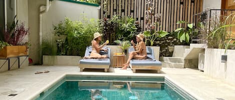 Relax by the pool surrounded by lush greenery and a serene atmosphere.