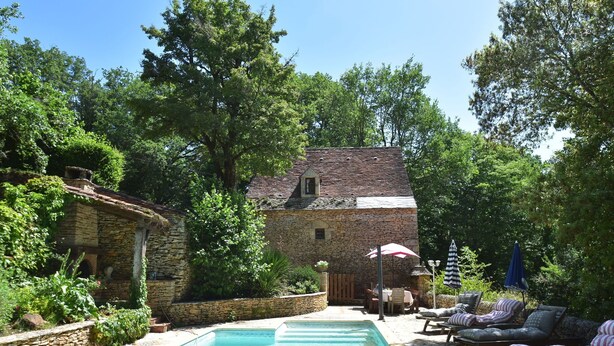 A stone building with a swimming pool, surrounded by lush greenery and outdoor seating. - Lovely Périgord holiday home in private forest (Besse)