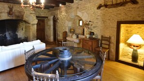 A rustic interior with exposed stone walls, a large wooden wheel table, and a fireplace. - Lovely Périgord holiday home in private forest (Besse)