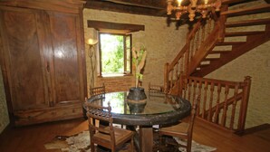 A wooden dining table with chairs, a glass top, and a vase with flowers. - Lovely Périgord holiday home in private forest (Besse)