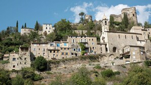 Un borgo collinare con edifici in pietra, alcuni con balconi, e una torre imponente.