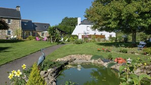 Ein friedlicher Garten mit Teich, Steinbauten und blauem Himmel.