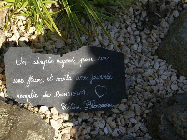 A black stone with white text and a heart symbol, surrounded by pebbles and grass. - Relaxing gîte with terrace, near Pont-Aven (Querrien)