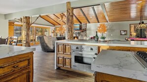 Una cocina amplia con una isla grande, vigas de madera y una chimenea de piedra.