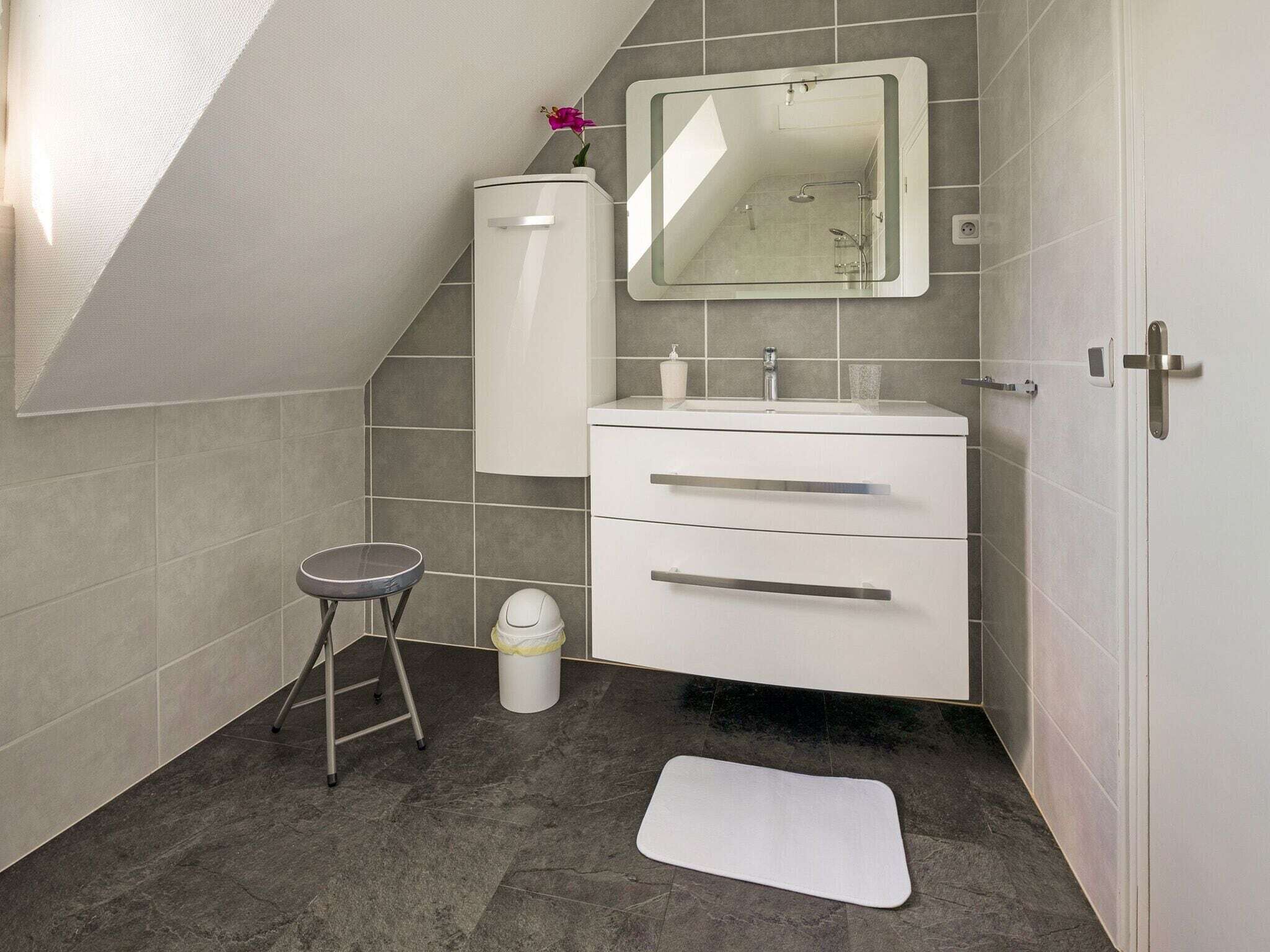 Une salle de bain moderne avec un meuble-lavabo blanc, un grand miroir et une douche.