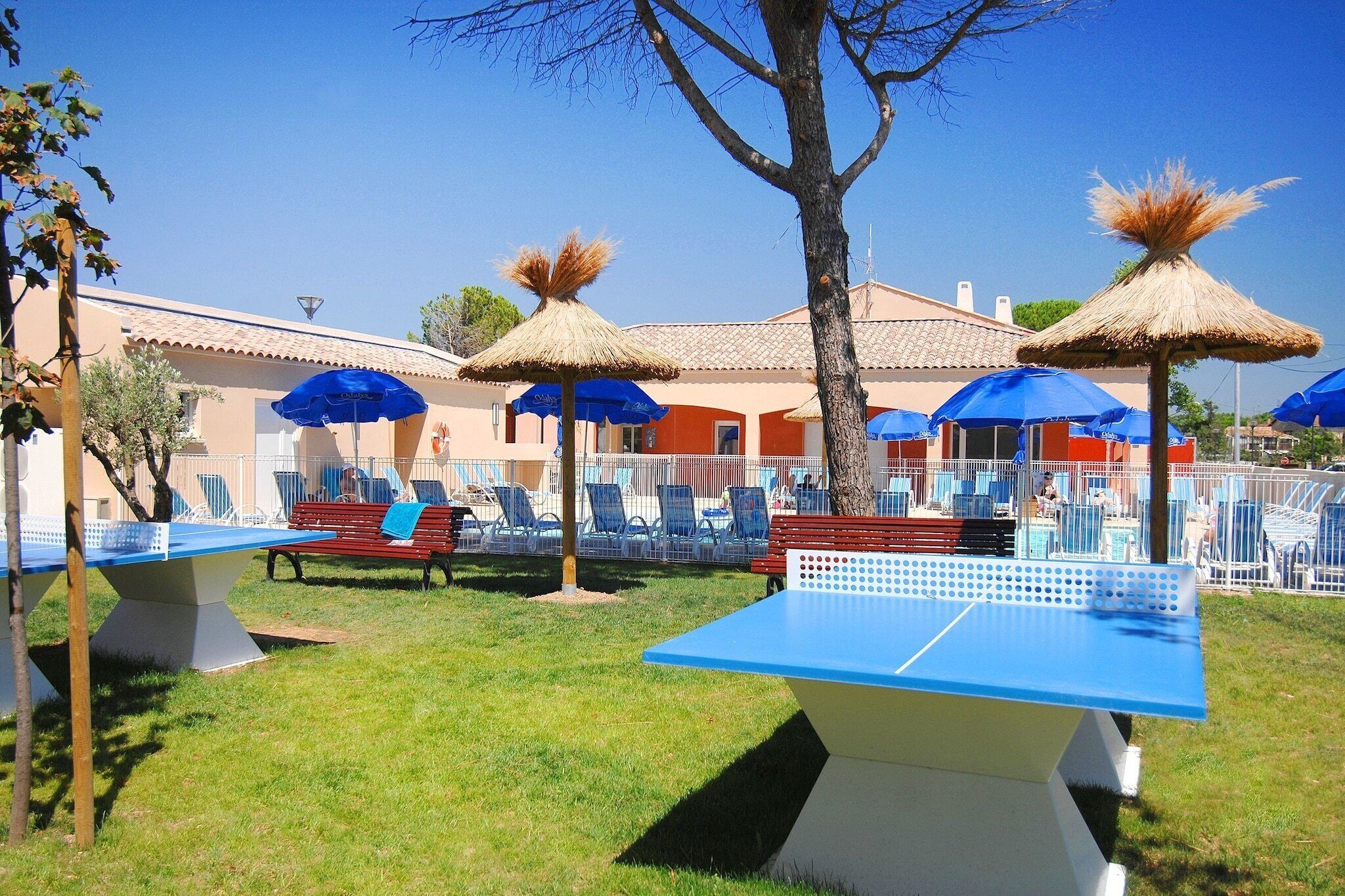 A poolside area with lounge chairs, umbrellas, and a ping pong table.