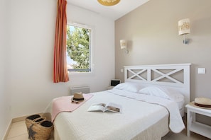 A bedroom with a bed, a window with curtains, a bedside table, and a wall-mounted lamp. - Maisonette in Aigues-Mortes near Flamingos (AIGUES MORTES)