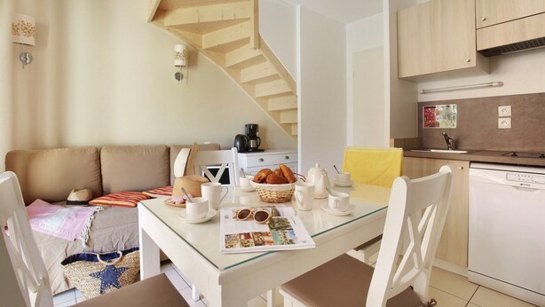 Uma cozinha moderna com área de refeições, uma escada e uma sala de estar com sofá.