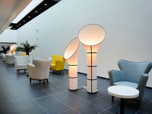 Ein modernes Interieur mit Sitzmöbeln, einer außergewöhnlichen Leuchte und einem Fliesenboden.