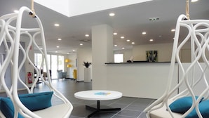 A modern interior with hanging chairs, a reception desk, and a tiled floor. - Maisonette in France with Terrace (Cap d'Agde)