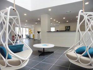 Decoração moderna com cadeiras penduradas, um balcão de recepção e piso ladrilhado.