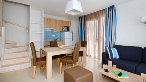 A modern living room with a sofa, coffee table, and dining area. - Maisonette in France with Terrace (Cap d'Agde)