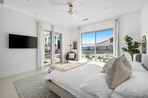 A modern bedroom with a large bed, a flat-screen TV, and a balcony with a pool view. - New! (PGA Signature) Platinum Magic! w/Gameroom! (La Quinta)