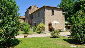 A stone building with a courtyard, surrounded by greenery. - Villa with outdoor pool and WiFi (Cortona)