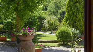 A garden with a large stone planter filled with flowers, surrounded by various shrubs and trees. - Villa with outdoor pool and WiFi (Cortona)