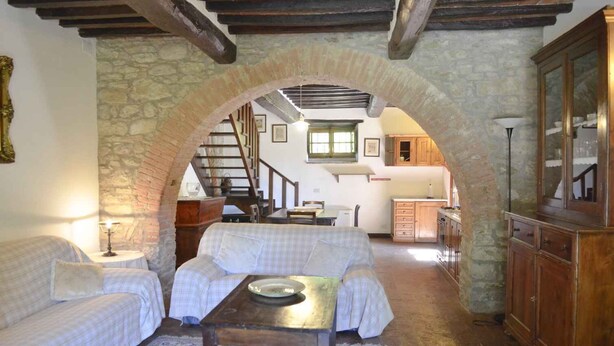 A cozy room with a stone archway, a sofa, a table, and a wooden cabinet. - Villa with outdoor pool and WiFi (Cortona)