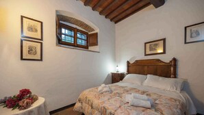 Una camera da letto con un letto di legno, un tavolino con fiori e quadri appesi alle pareti.