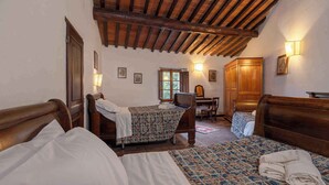 Una stanza con due letti, testiere in legno, una scrivania e una sedia.