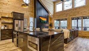 A modern kitchen with a large island, stainless steel appliances, and a built-in TV.