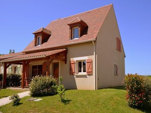 A two-story house with a sloped roof, wooden porch, and shutters.