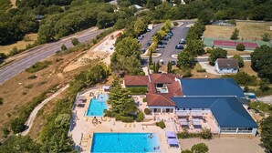 An aerial view of a resort with a large swimming pool, multiple buildings, and a parking area. - Villa in Lanzac with Private Garden (Lanzac)