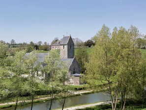 A stone church with a tower, surrounded by greenery and a river. - Gouvets Family Retreat (Gouvets)