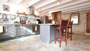 Een moderne keuken met grijze kastjes, een centraal eiland en een stenen muur.