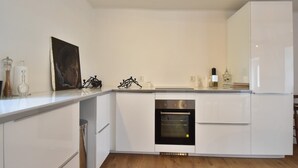 Moderni keittiö, jossa on valkoiset kaapit, sisäänrakennettu uuni ja ruostumattomasta teräksestä valmistettu pesuallas.