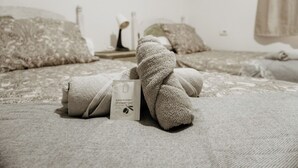A neatly made bed with a towel and a bottle of shower gel.