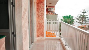 A balcony with a tiled floor, a white railing, and a view of the sea.