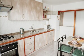 Cucina con piano cottura a gas, lavello, forno a microonde e mobili in legno.