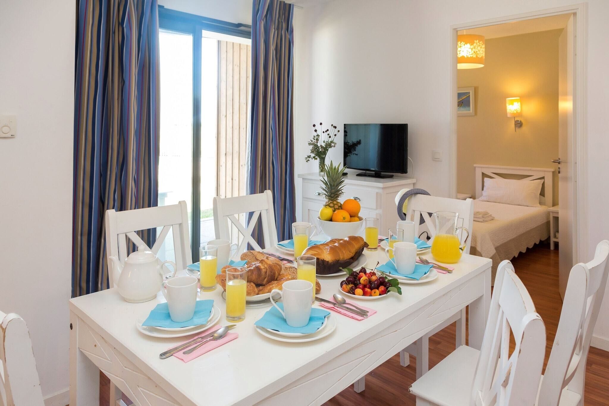 Ein Frühstückstisch für zwei Personen, gedeckt mit Croissants, Obst und Saft.