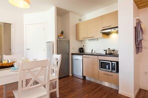 A compact kitchen with a refrigerator, microwave, and stove.