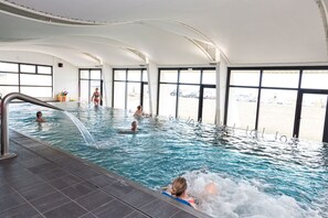 Ein Hallenbad mit klaren Fenstern, gefliestem Boden und einer Person im Wasser.