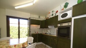 A kitchen with green cabinets, a tiled backsplash, a microwave, an oven, and a dining area with a table and chairs. - Holiday home in Vic-sur-Seille near the forest (Vic-Sur-Seille)