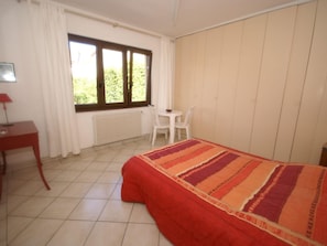 Une chambre à coucher avec un lit, un bureau, une chaise et une fenêtre avec des rideaux.