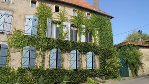 A two-story building with a red-tiled roof, covered in green ivy, and multiple windows with blue shutters. - Holiday home in Vic-sur-Seille near the forest (Vic-Sur-Seille)