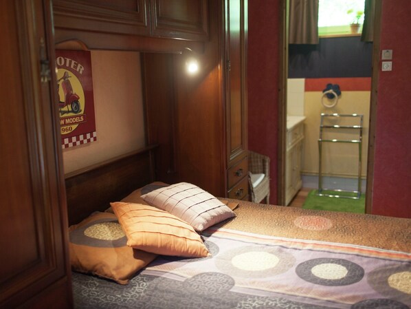 A compact bedroom with a bed, pillows, a poster, and a small dresser. - Cozy chalet with garden and pond view (Le Ponchel)