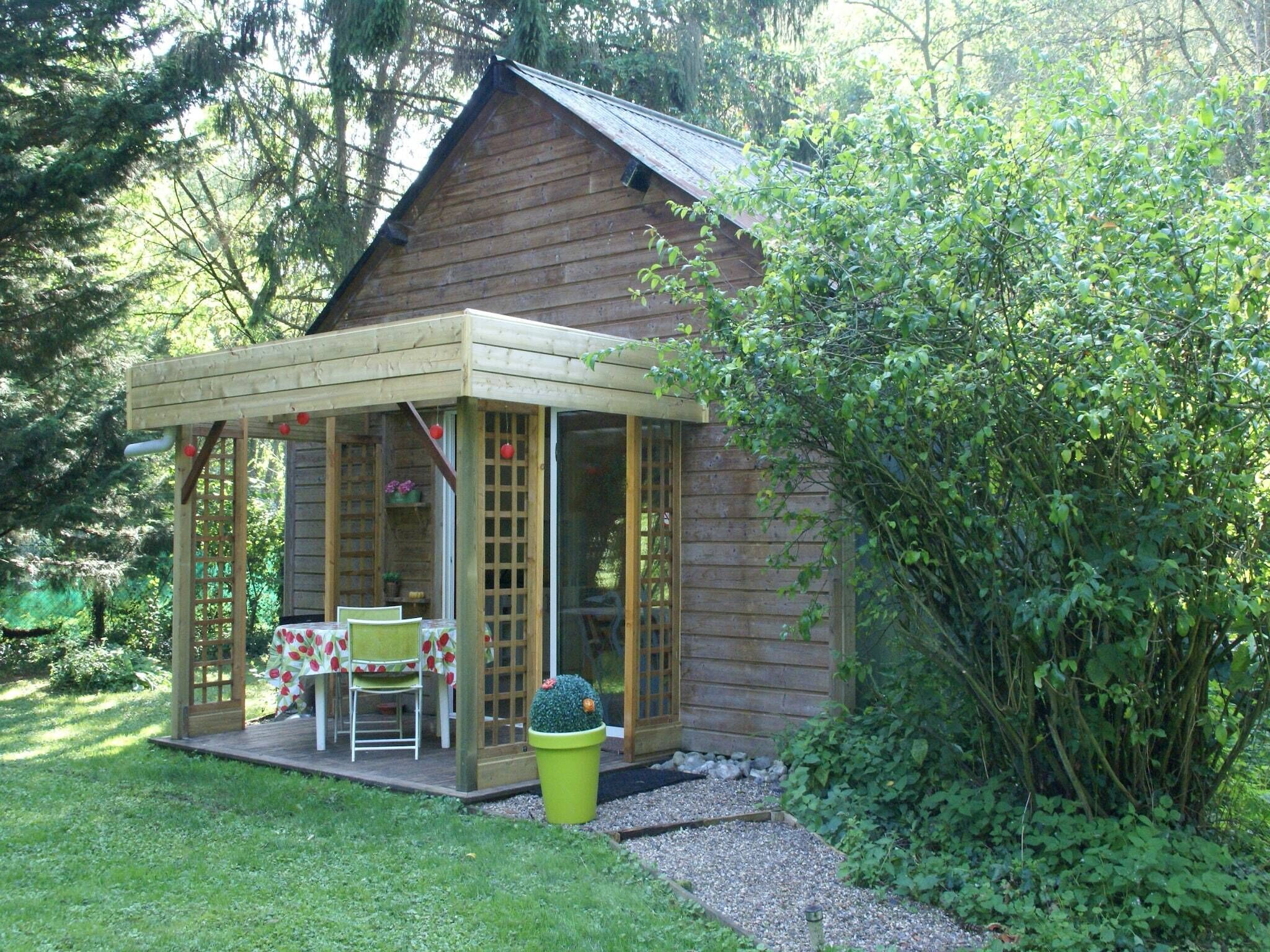 Une cabane en bois avec un patio couvert, une table avec des chaises et une plante en pot.