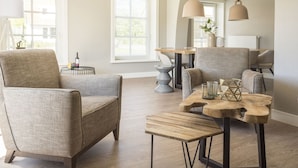 Una sala de estar moderna con un sillón gris, una mesa de centro de madera e iluminación colgante.