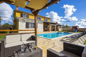 A poolside area with wicker furniture and a stone patio.