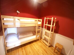 Habitación con literas, una escalera de madera y un taburete pequeño.