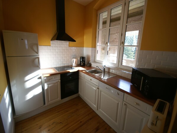 A compact kitchen with white cabinets, a stainless steel refrigerator, a black range hood, a microwave, and a window with blinds. - House in Rhone Valley near Ski Resorts (Serrieres en Chautagne)