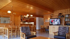 Un interior de madera con comedor, cocina y televisor.